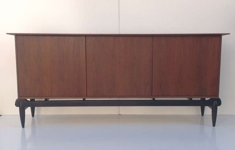 This is absolutely incredible buffet designed by Greta Grossman for Glenn of California in the 1960s floats on a dark walnut frame.
Three doors open to reveal two felt-lined silverware drawer and three more drawers and shelving.