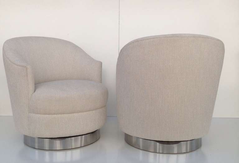 A pair of swivel chairs designed by Karl Springer.
Newly reupholster in a light white cotton fabric, wood base with a chrome band. 
These chairs swivel 360°