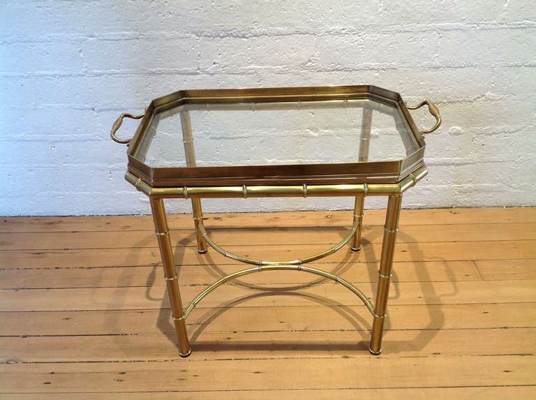 A brass tray table by Mastercraft.
The brass and glass tray lifts off the stand to be used for serving.