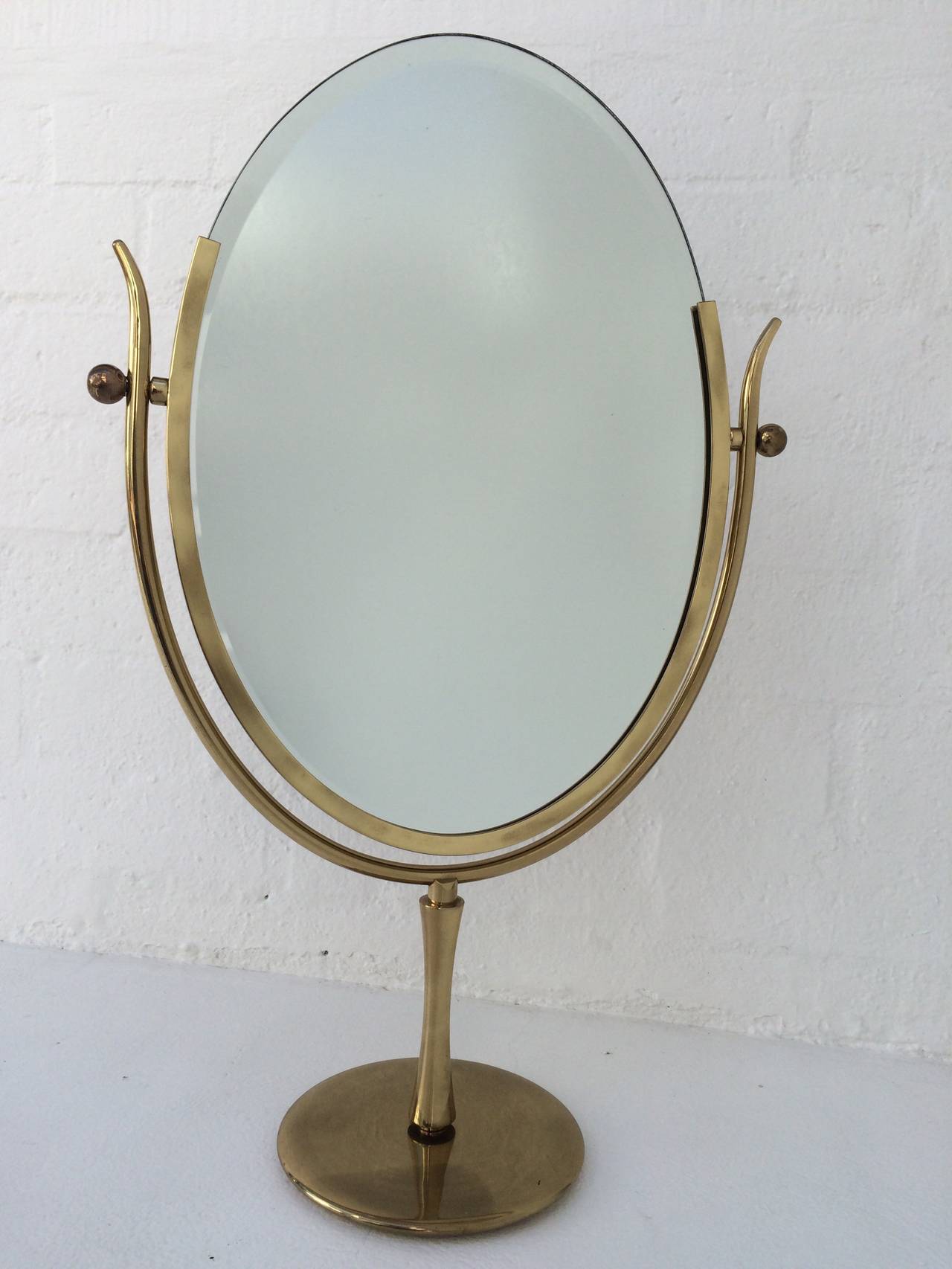 This wonderful table mirror is designed by Charles Hollis Jones. 
The beveled mirror is supported by a heavy brass stand and has brown leather on the back. 
circa 1970s.