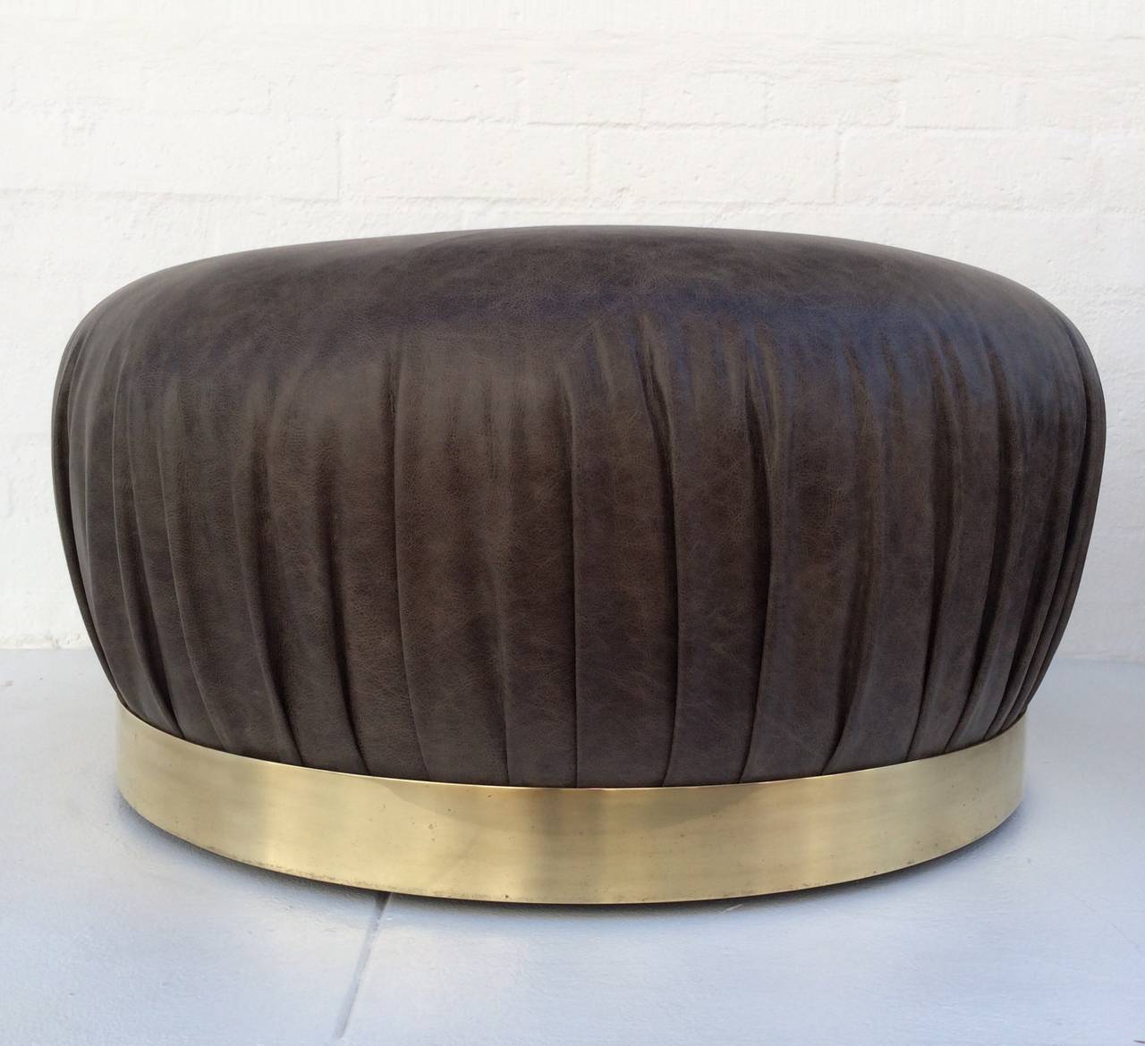 Un ottoman en cuir et en laiton lourd à grande échelle conçu par Karl Springer.
Nouvellement remeublé dans un cuir gris vieilli.
Le fond rond en laiton lourd est doté de roues cachées, ce qui facilite le déplacement de ce magnifique ottoman.