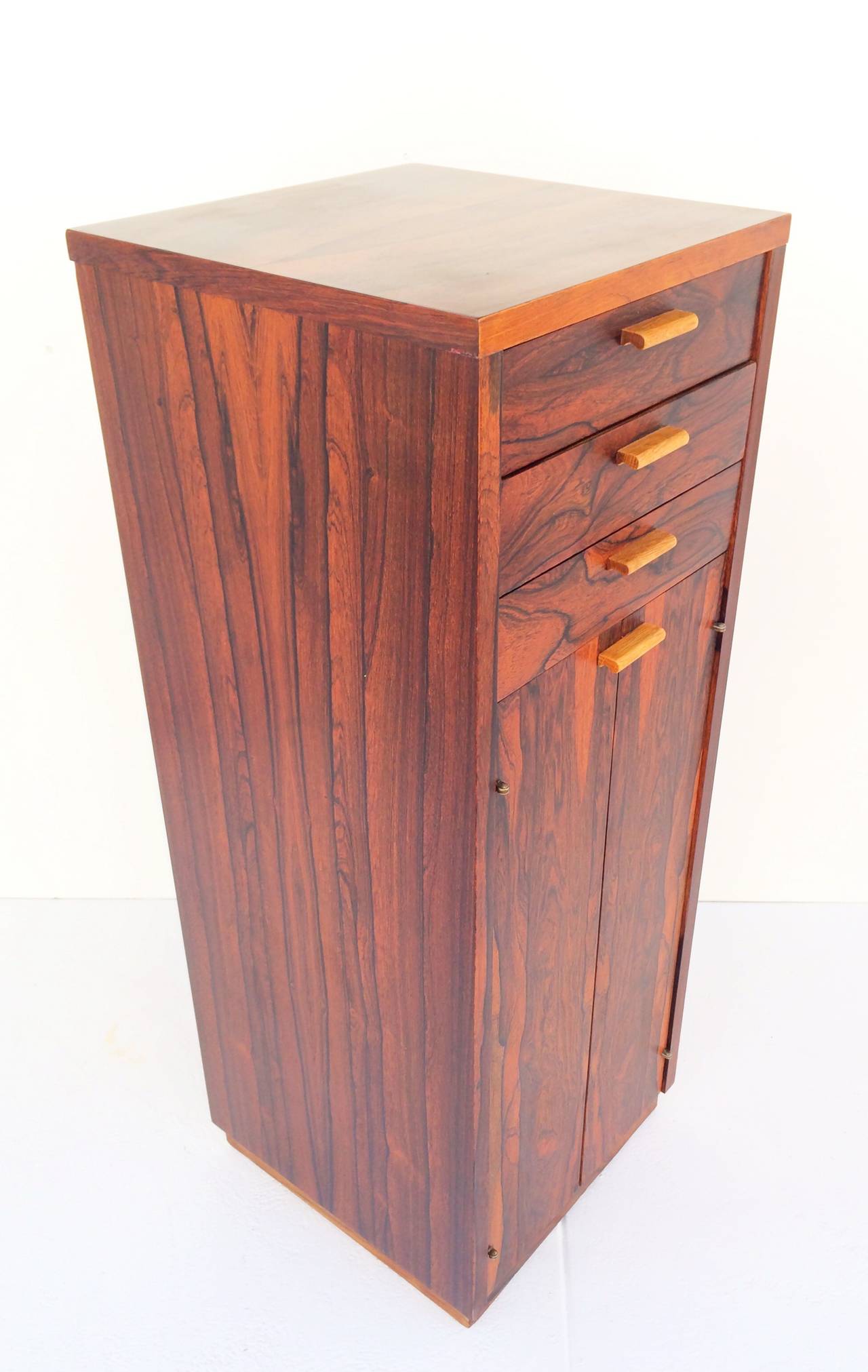 A stunning small-scale rosewood gentleman's chest. 
This chest has three drawers at the top with double doors below that open to reveal an adjustable shelf and a finished rosewood interior.
This piece has a finished rosewood back, making placement