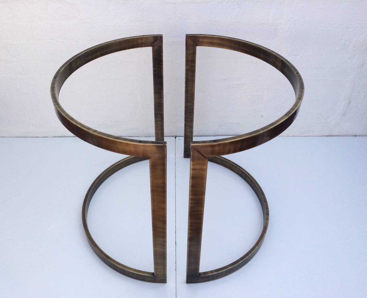 A two-piece antique brass dining table base designed by Milo Baughman. 
This attractive base can be set up many different ways as each half is a half circle and can support either a round or square glass top. 
Together the base measures 29
