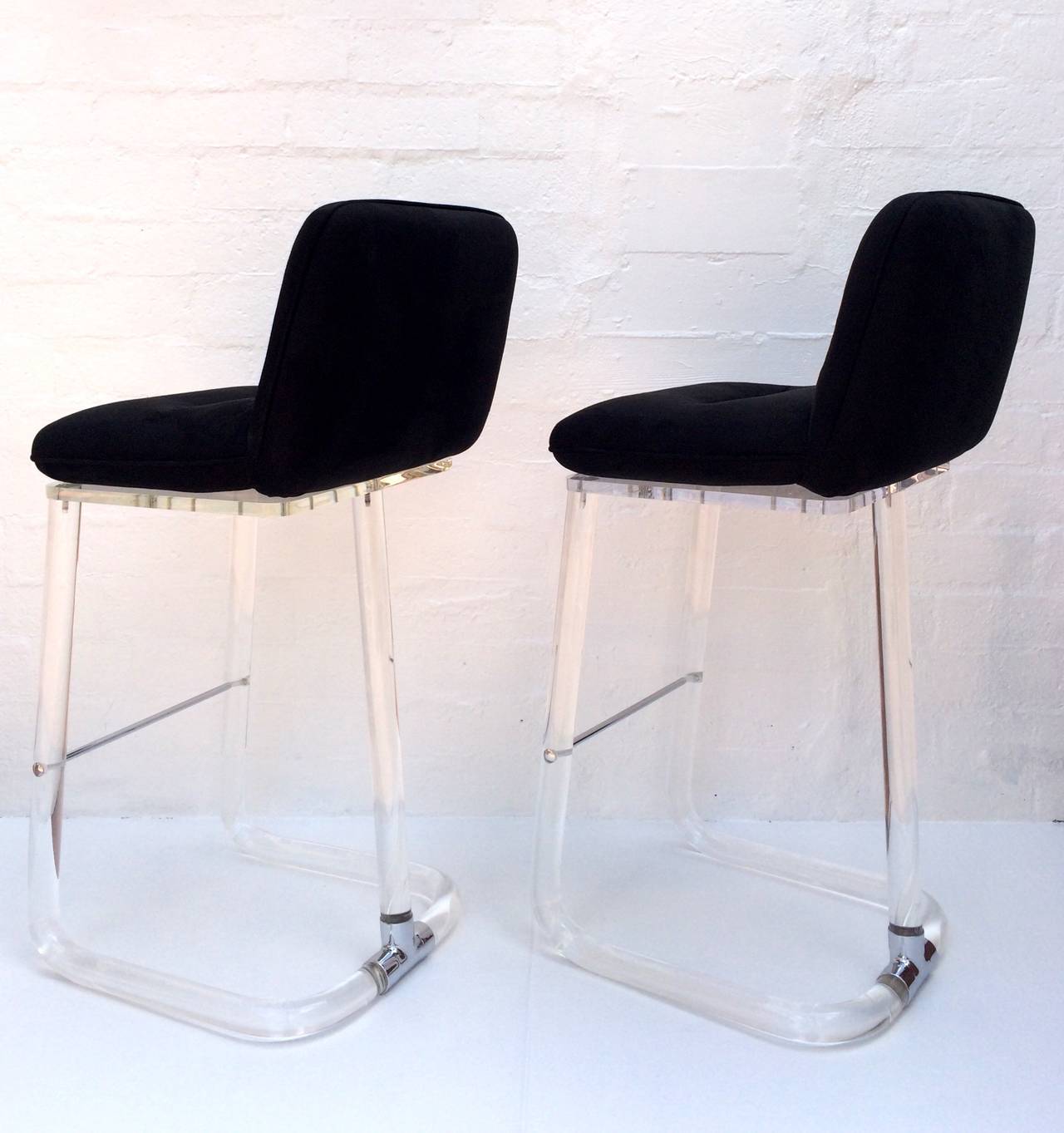 These stunning stools are acrylic with polished chrome foot bar and polished chrome t-bar holding the back back support and bottom together. 
They have the original black ultrasuede leather upholstery.  
Newly professionally polished. 
Both