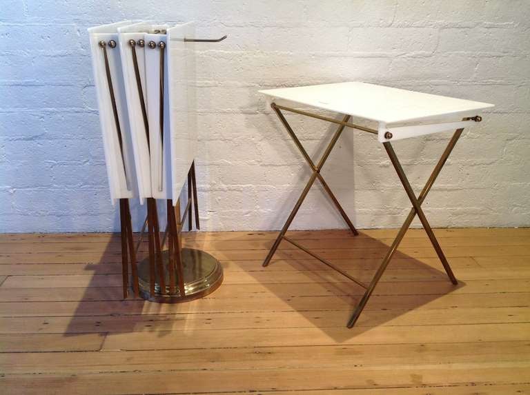 Set of four folding tray tables designed by Charles Hollis Jones.
These tables are made of white acrylic and brass, with a brass stand that holds them when not in use.