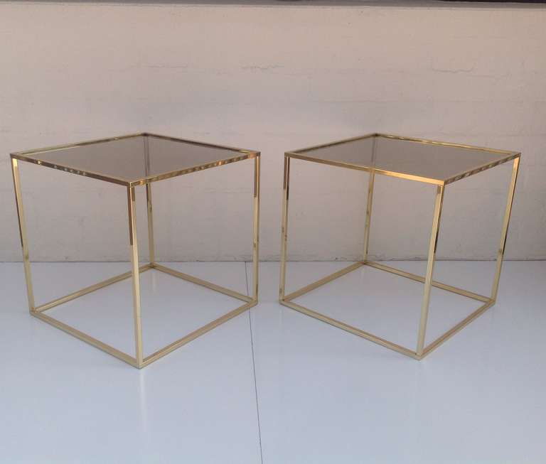 A pair of cube table consisting of newly polished Brass with new glass tops. 
Designed by Milo Baughman.