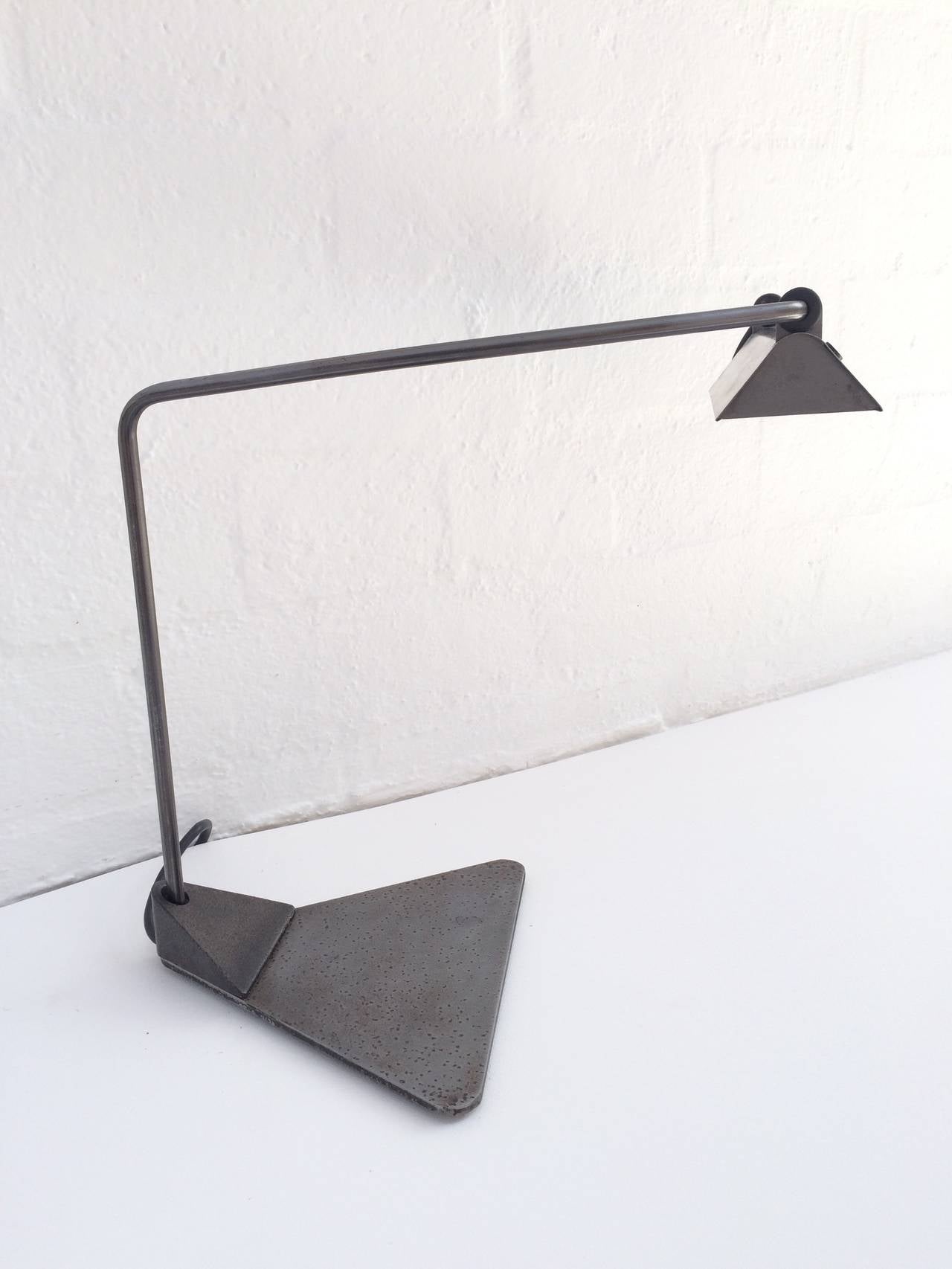 Lampe de bureau conçue par Ron Rezek. 
Cette lampe présente une finition en acier brut, un bras et un abat-jour réglables,
vers les années 1980.