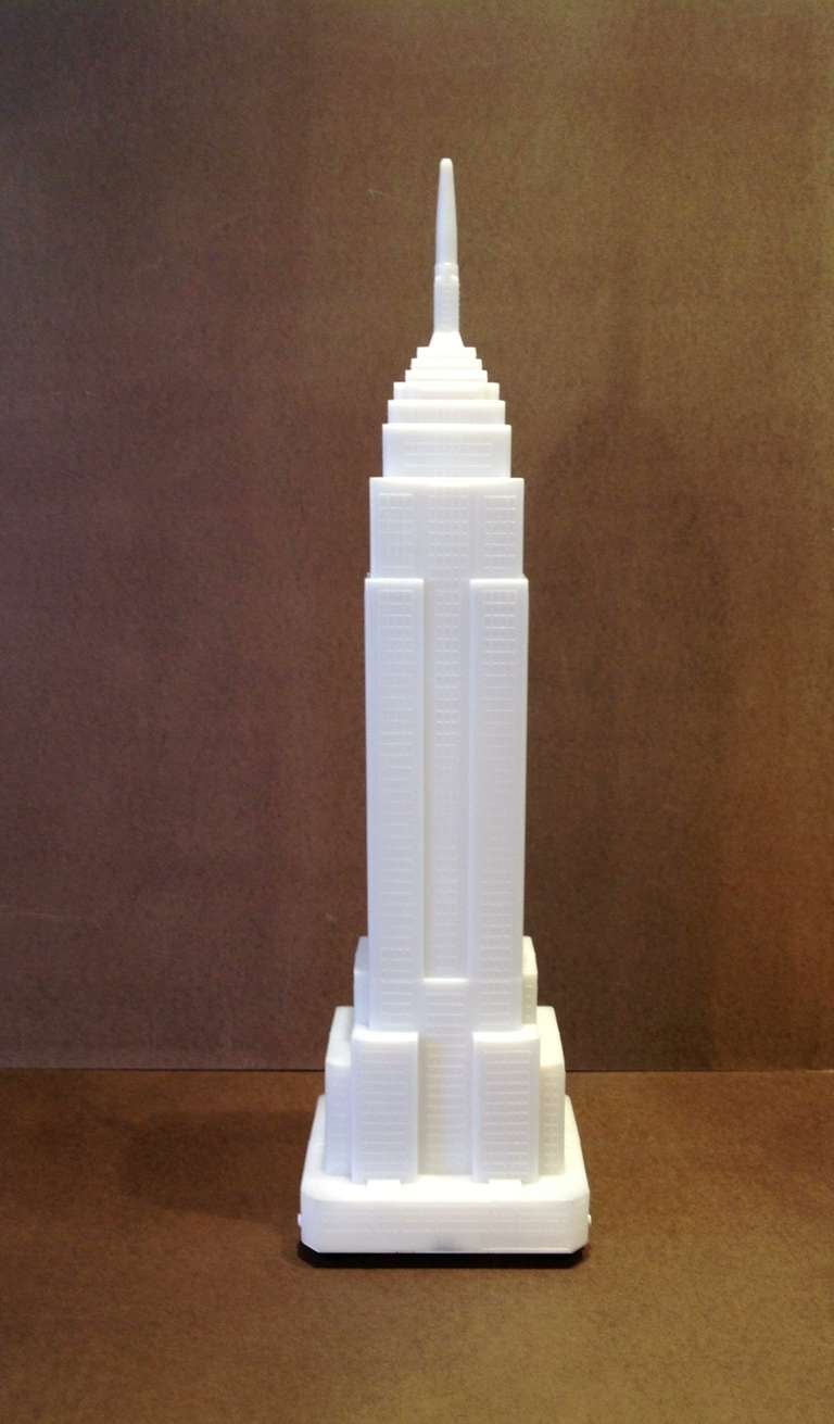 This lamp is constructed with a translucent white plastic shell in the form of the Empire State Building. Within the building's shell is a fluorescent tube light that illuminates the building from within. This architectural lamp shows incredibly