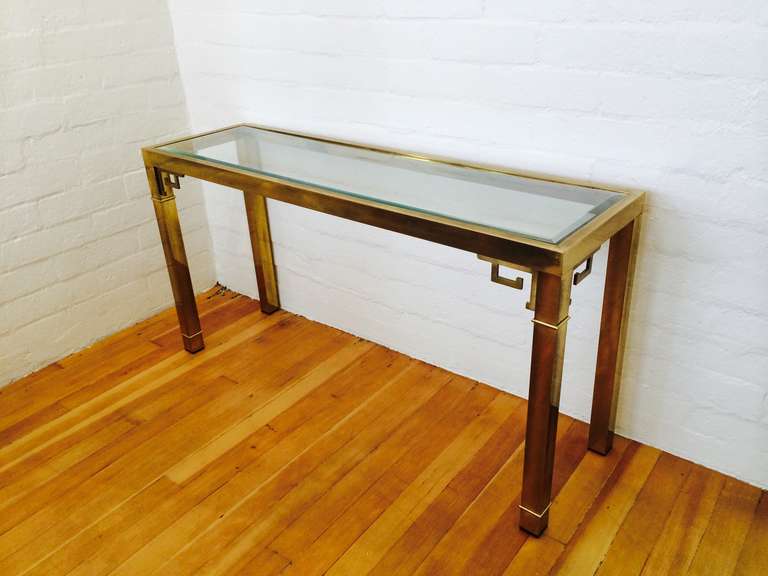 A brass with inset glass top greek key console table by Mastercraft. 
Consist of antiqued brass with beveled glass.