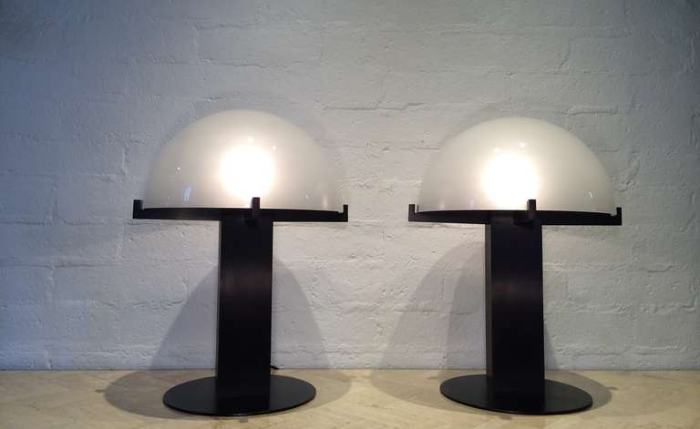 A pair of black table lamps with white frosted glass shades designed by Ron Rezek, circa 1980s.  
Built in dimmer switch.