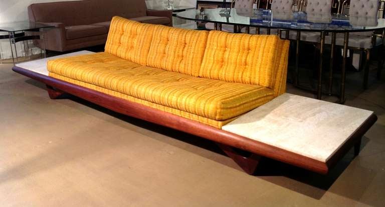 An Adrian Pearsall sofa in original fabric. This very sculptural sofa floats on a walnut base and has built in side tables with inset travertine tops.
