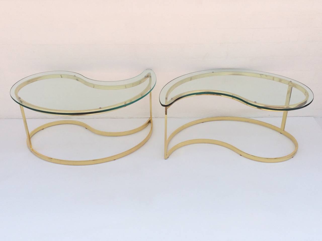 A pair of polished brass and glass cocktail or coffee tables designed by Milo Baughman. 
Consist of polished brass frames and 1/2 thick glass top. 
These fun tables can be used together as a cocktail table or as side tables.