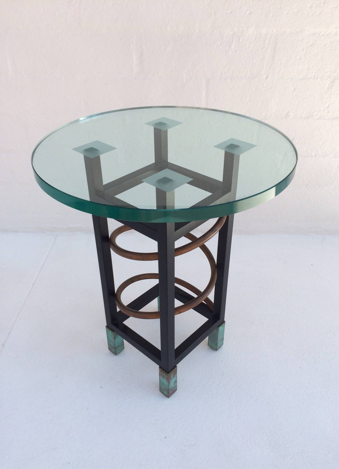 Cette table d'appoint de style Memphis des années 1980 est constituée d'acier peint avec des tubes en cuivre et des pieds en cuivre. 
Le plateau rond en verre a une épaisseur de 3/4 de pouce.