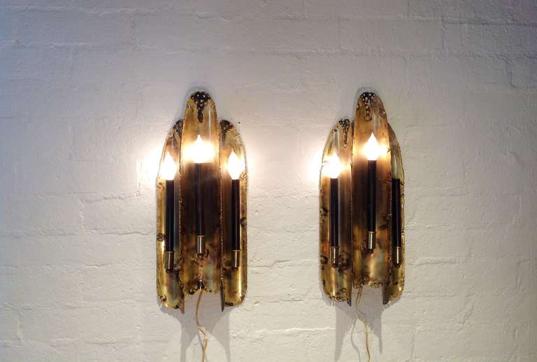 A pair of brass brutalist wall sconces each consisting of three candlestick style lights.  
Designed by Tom Greene for The Feldman Co..
Circa 1970s
Newly rewired.
