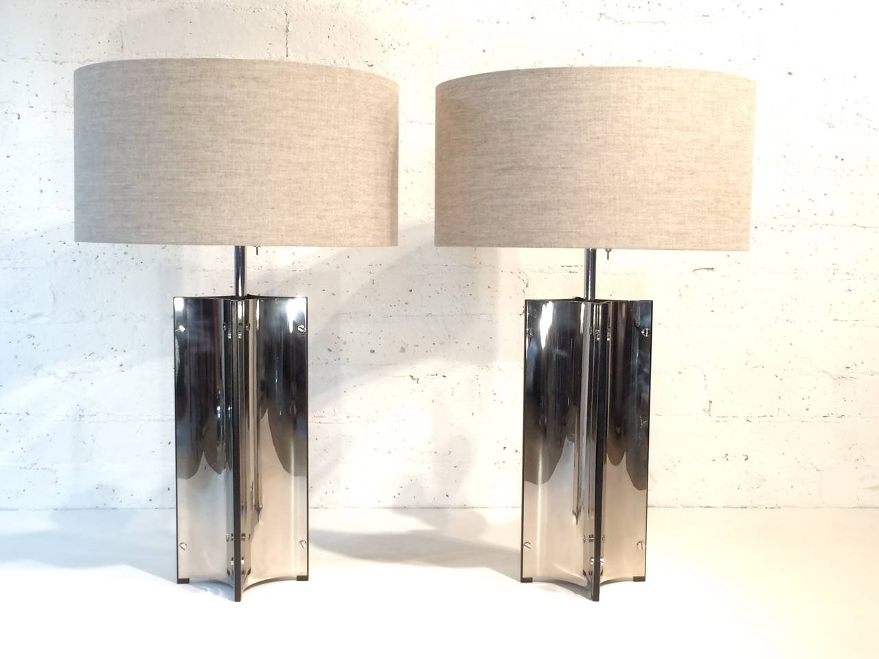 A pair of polished chrome with black lacquered steel table lamps. 
Designed by Gerald Thurston and made by Lightolier.  
These lamps retain the original Lightolier hanging paper tag ( see photos)
Newly rewired and new oatmeal linen shades.