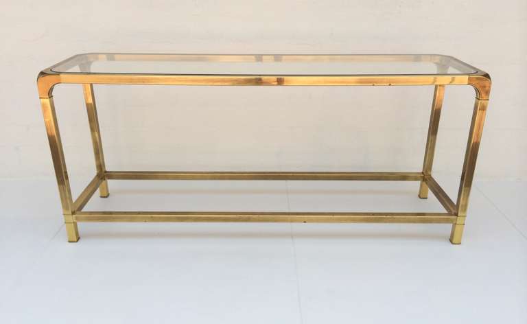 A antiqued brass console table with glass inset top made by Mastercraft.
