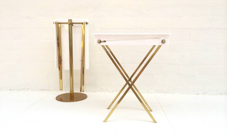 A pair of hard to find small scale  folding tray tables with stand designed by Charles Hollis Jones. 
These trays are polished brass with white acrylic tops that have a hole in the top to hang on the polished stand.
Each table is 25.25