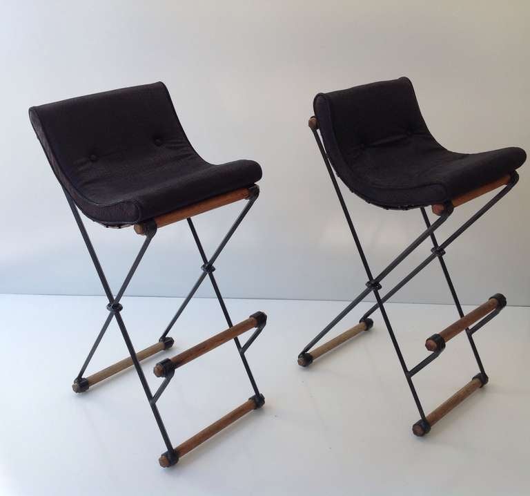 a pair of wrought iron and oak  X frame high back bar stools designed by Cleo Baldon.
Newly recovered removable seat cushions done is a black leather that have an eel like texture.