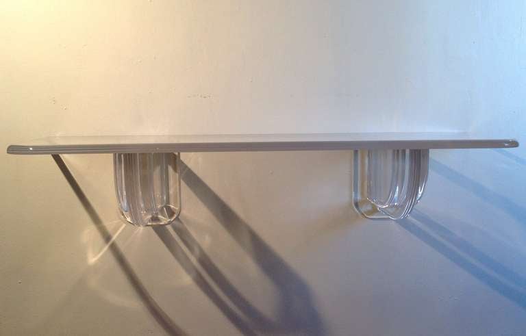 This thick acrylic shelf resting  on  two massive sculptural supports that mount to the wall and have chrome caps that cover the mounting screws.
 Comes from a Palm Springs Estate that was done by Steve Chase.
Has just been professionally polished