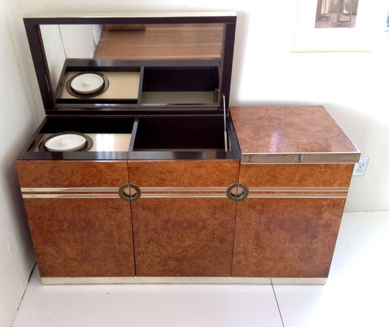 A signed burlwood bar designed by Pierre Cardin from the 1970s
The top lift up to showcase to hidden ice bucket and mirror.
Has brass accents.
There are three doors that open to storage and one drawer for bar tools. the inside and top bar are