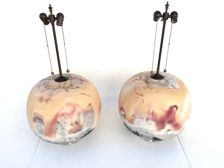 This pair of fantastic ceramic lamps are signed ( A Zigulis) and dated 1985.  
They came out of a Palm Springs Estate that was designed by Steve Chase in the 1980s. 
Acrylic bases with bronze hardware. 
Their larger scale and beautiful fire