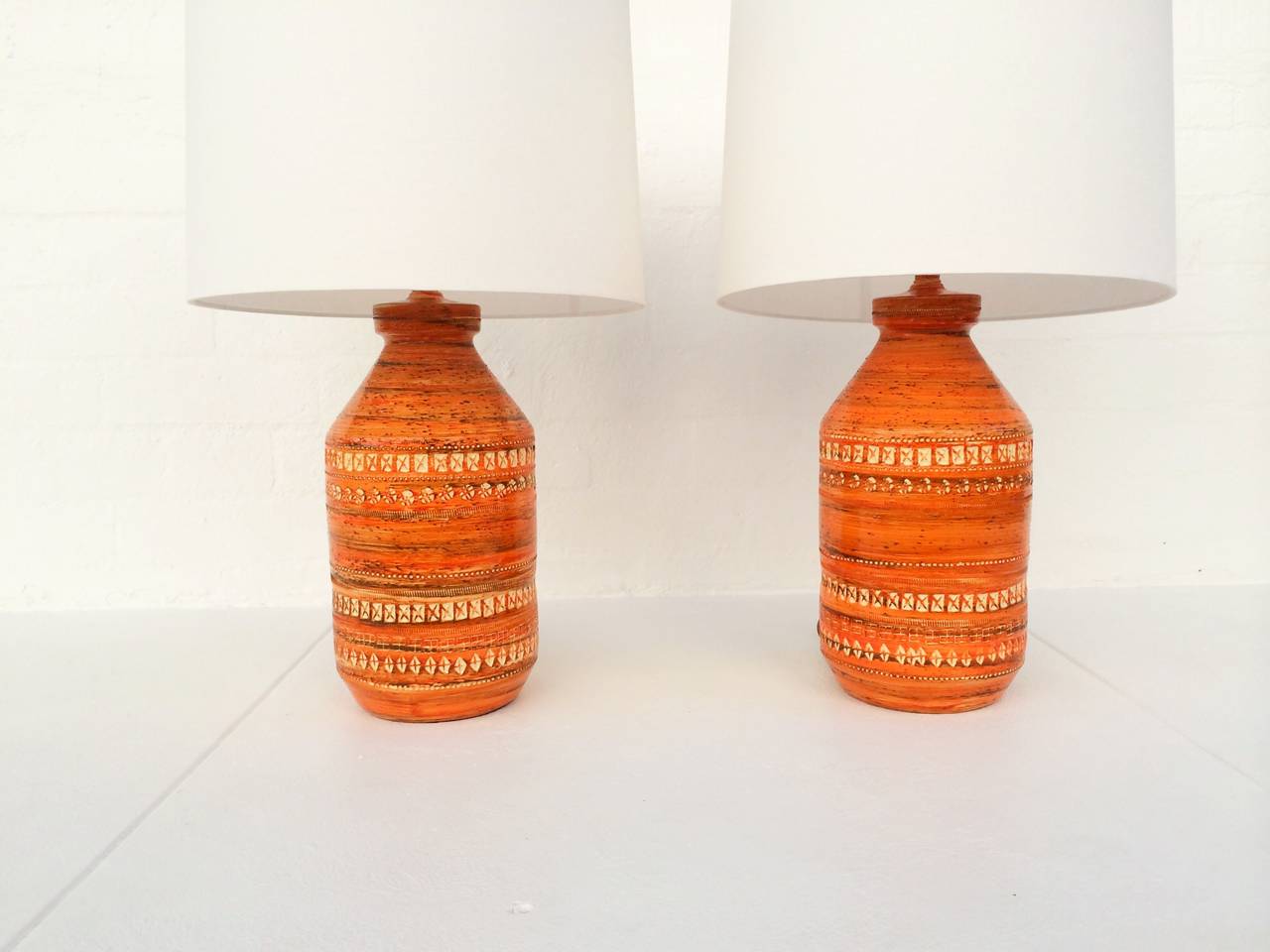 Beautiful pair of orange Italian ceramic lamps by Aldo Londi for Bitossi.

New linen shades. Rewired with new brass sockets and brown cloth cord.
The diameter of the base without shade is 9