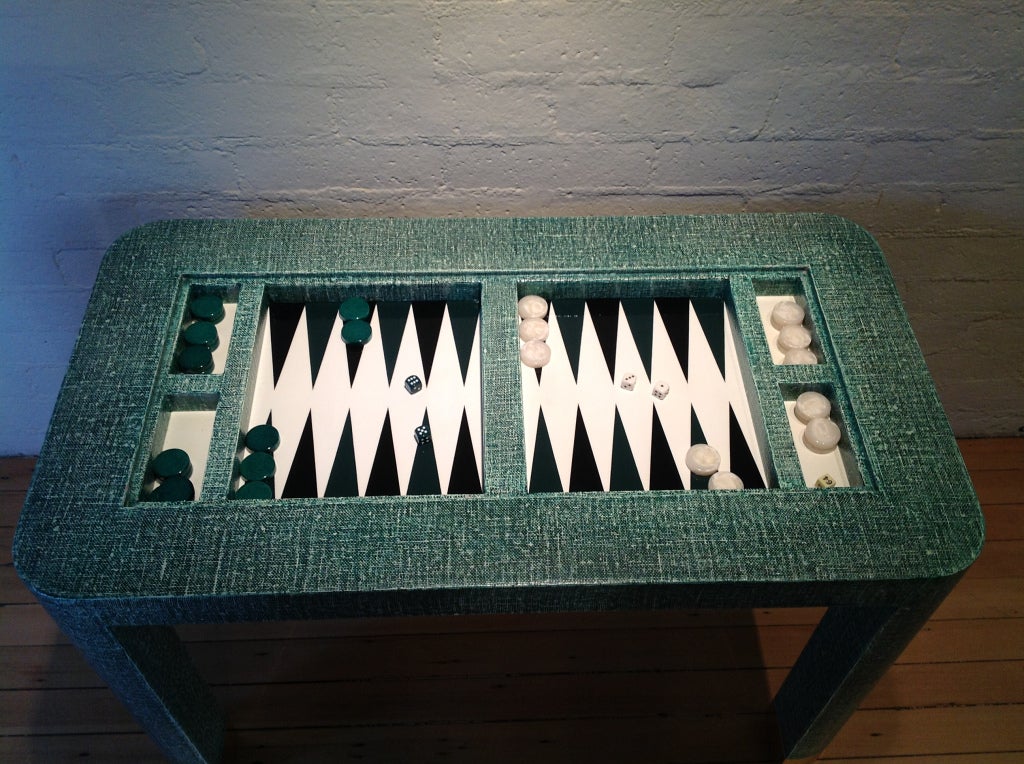 An Amazing backgammon table by Karl Springer.
This backgammon table came from a Indian Wells estate designed by Stephen Chase.
The table is covered in a green grass cloth with brass covering at the feet, and comes with a Glass top and all the game