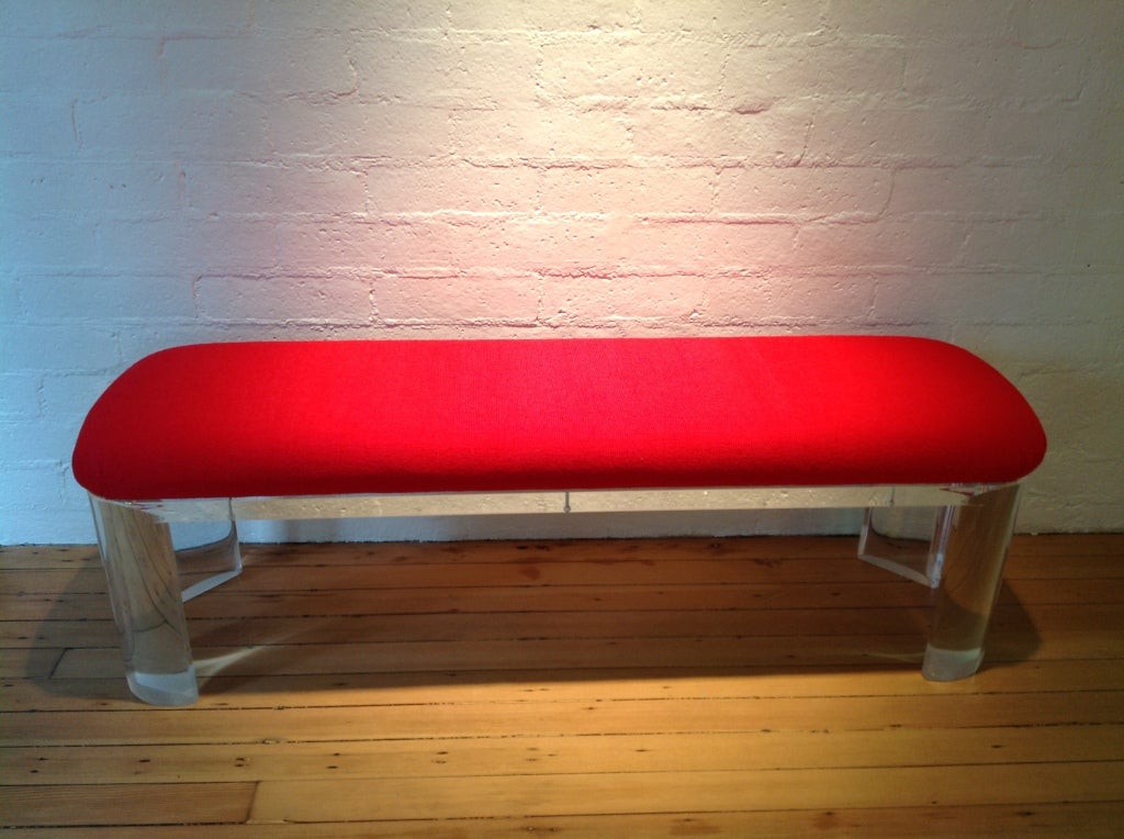 A Lucite bench in the style of Karl Springer,recovered in a red knoll fabric.
