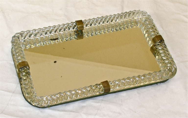 Mirrored glass vanity tray surmounted by thick twisted mouth blown glass with decorative brass straps. Glass rope is created from a single piece of clear twisted and fold glass.
