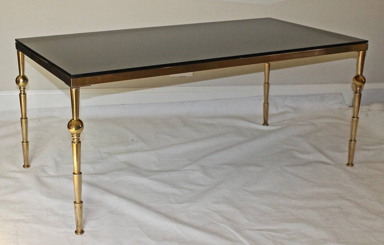 Large scale French Moderne style brass cocktail or coffee table with reverse painted black glass top.