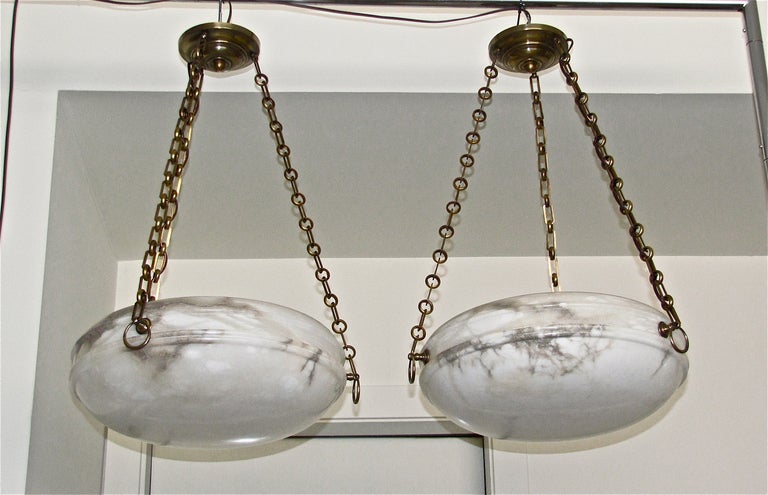 Beautiful pair of French alabaster light pendants with bronze fittings. Interior lighting has been refitted to keep light bulbs away from alabaster and provide a more even light distribution.  Uses 3-40 watt max candelabra base bulbs.