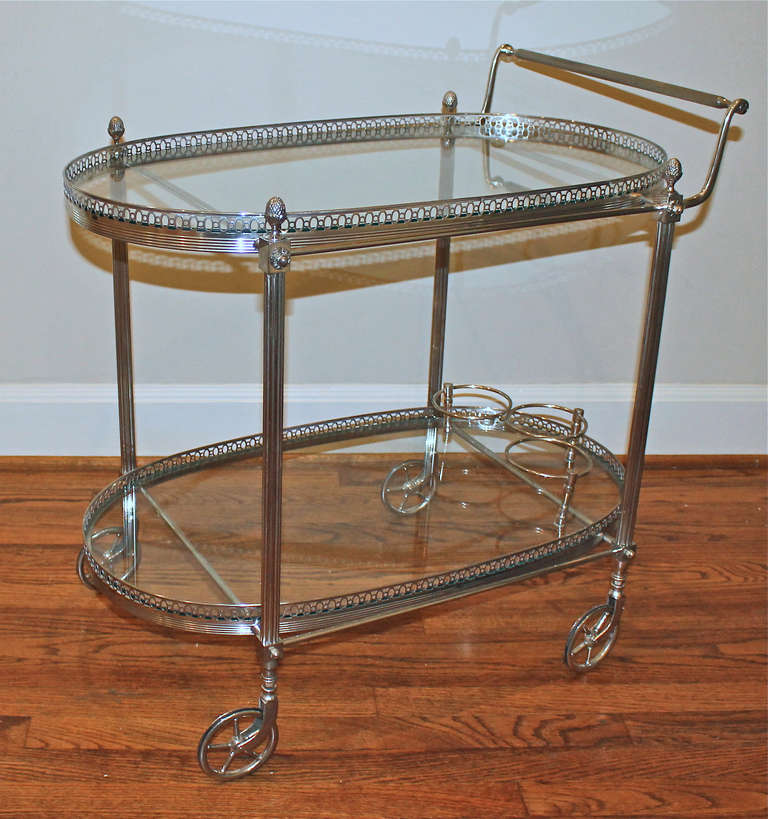 Rare 1940's French 2 tier silver plated bar cart with inset glass shelves and bottle holder. Refined details in the delicate gallery, fluted legs, acorn finials and wheels.