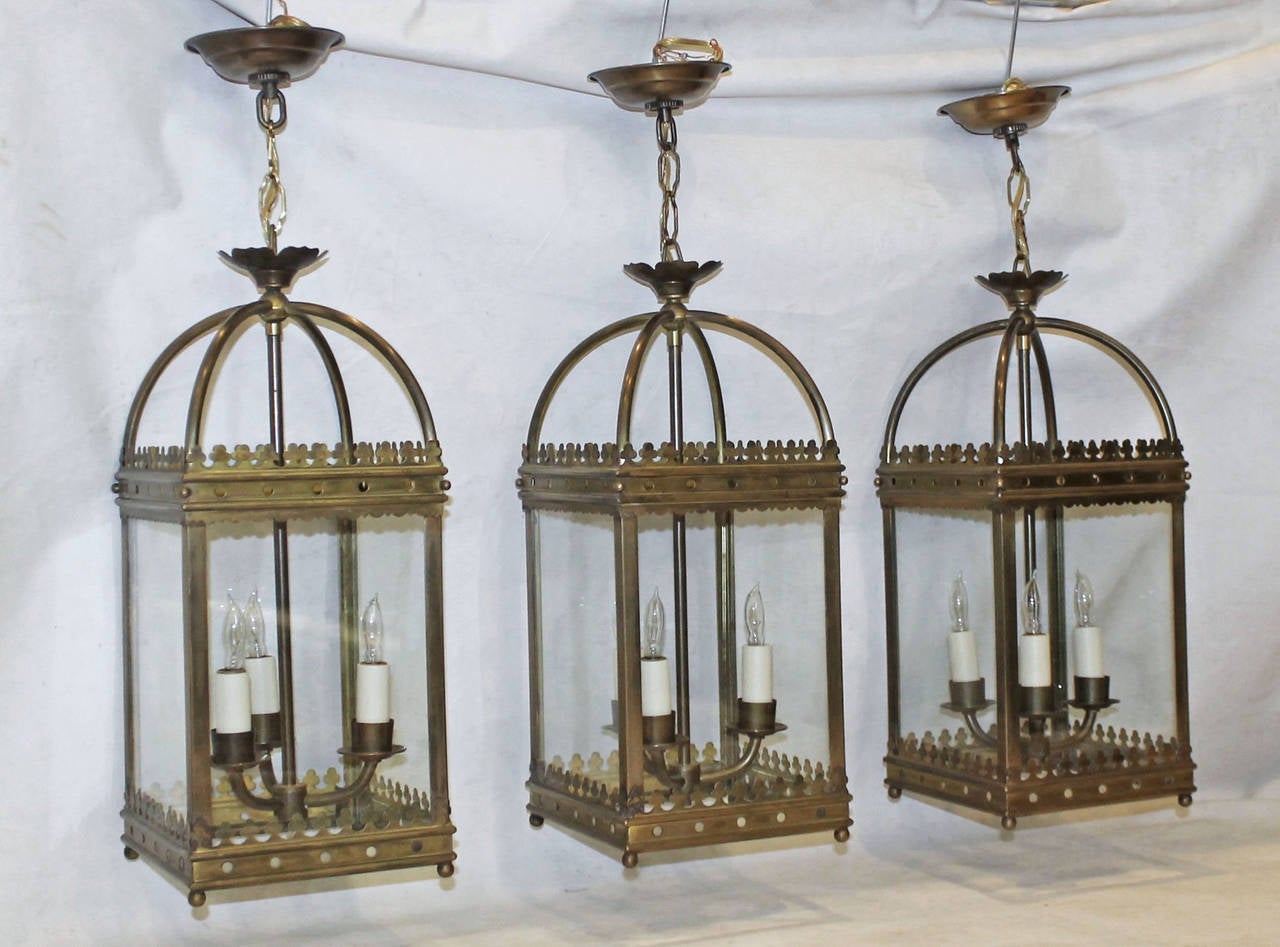Set of three (3) high quality English style brass hall lanterns or pendants with glass panels each and 3 light arm light clusters. Fixture size is 18