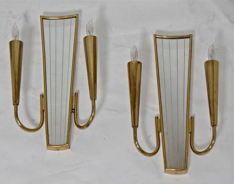 Pair of 2 light brass wall sconces in the manner of Gio Ponti. Mirrored backs have etched vertical stripes. Nice patina to lacquered brass. Each sconce uses 2 40 watt max candelabra base bulbs. Newly wired. A second pair is available.