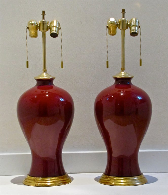Pair of beautiful early 20th Century Chinese Oxblood porcelain vases mounted on 23k water gilt turned wood lamp bases. Rewired.
