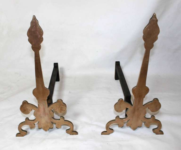 Pair of heavy bronze andirons great overall patina. A stylized version of a classic silhouette that can blend with both traditional and eclectic interiors.