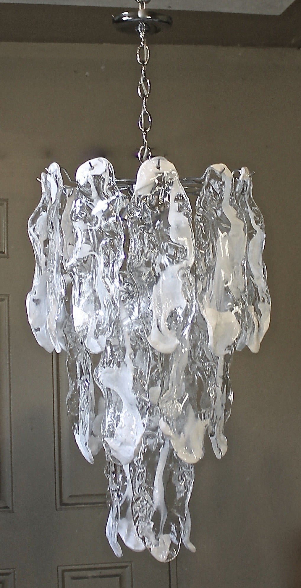 Large clear and white glass icicle shape panels by Mazzega, Murano Italy. Newly chrome plated frame with 9 - 40 watt max candelabra base size bulbs, newly wired. Overall height including chain and ceiling canopy is 44