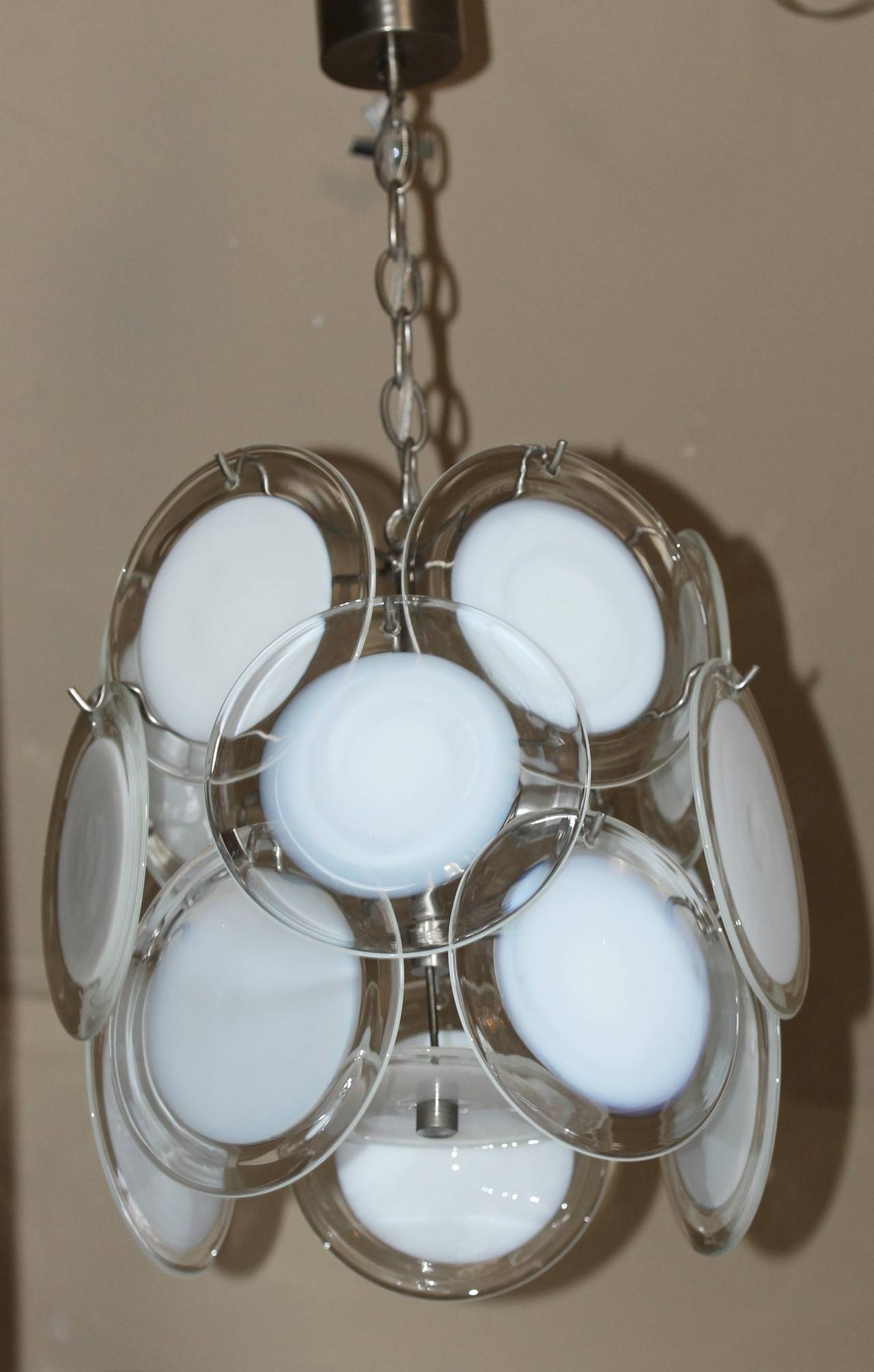 Clear and white disc Murano Italian glass three-light chandelier. Satin chrome plated metal frame. Uses 3 - 40 watt max candelabra base bulbs, newly wired. Overall height with chain 24