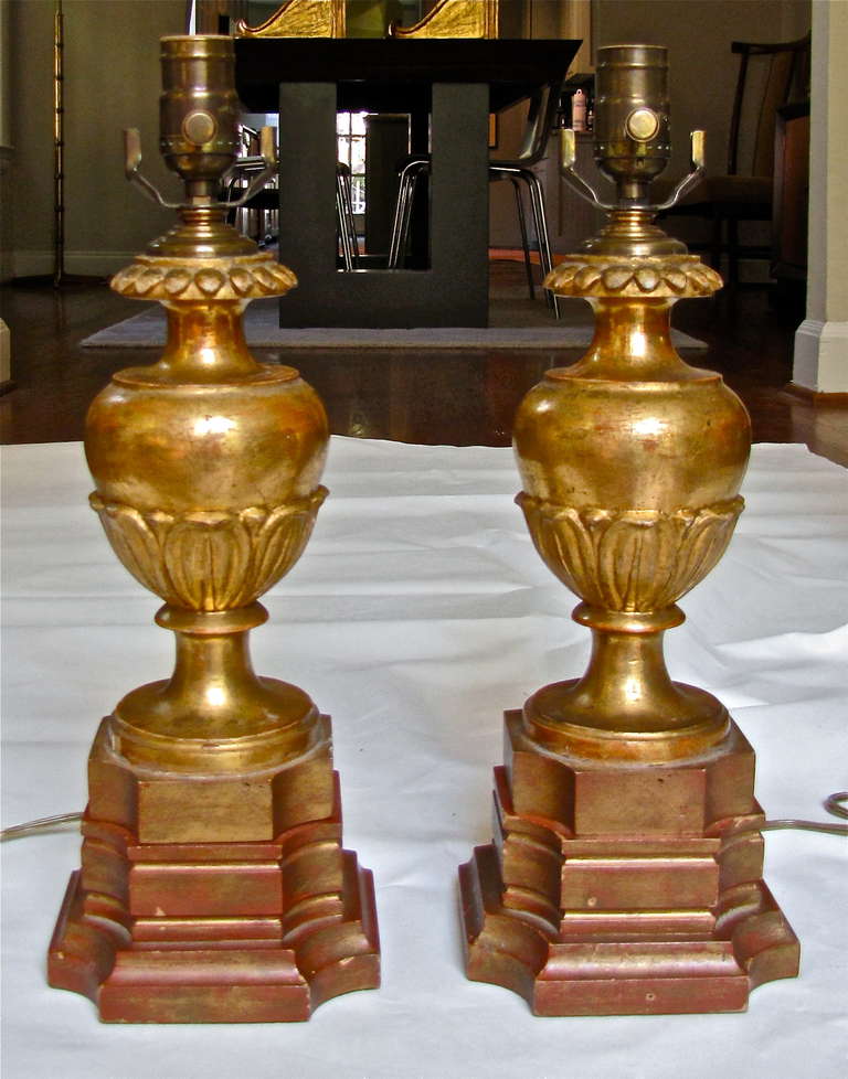 Pair of Italian water gilt carved wood candlesticks converted to lamps with later custom wood bases in a coordinating painted finish. Brass hardware fittings. Newly wired.
