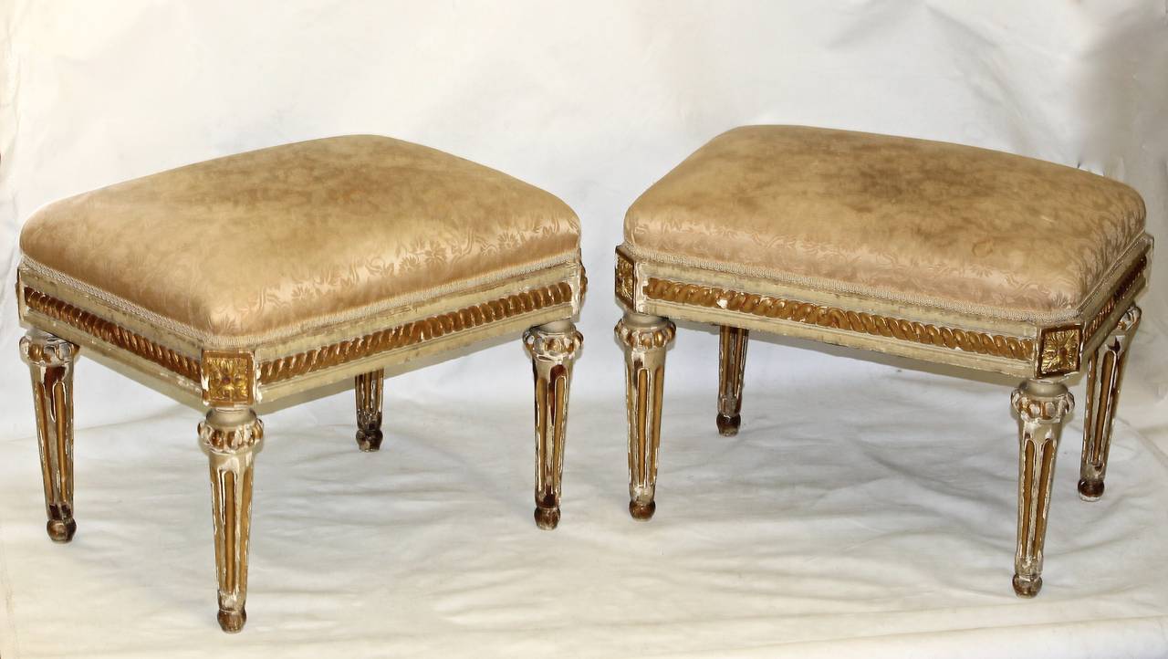 Pair of late 19th century French Louis XVI style parcel gilt and painted stools or benches. Excellent carving and detailing and well scaled for contemporary interiors. Needs new upholstery.