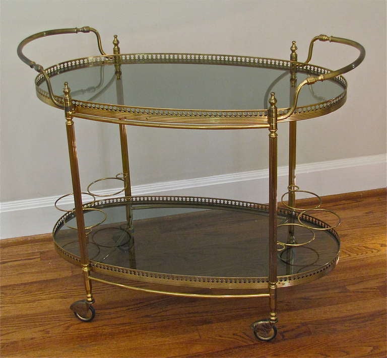 Attractive vintage French brass bar cart with reeded legs and two tinted glass shelves. Nice detailing including bottle/decanter holders.