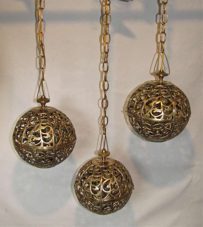 Trio of high quality Asian pierced brass pendants newly wired with new triple cluster light sockets and solid brass fittings. Includes chain and ceiling cap, ceiling drop can be adjusted as needed. All 3 Pendants 9