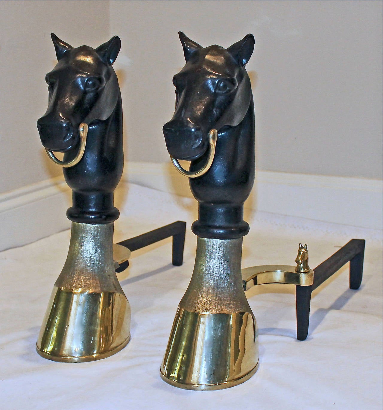A very handsome pair of bronze or brass and cast iron andirons with a horse head and hoof motif and horse head finials at the base.