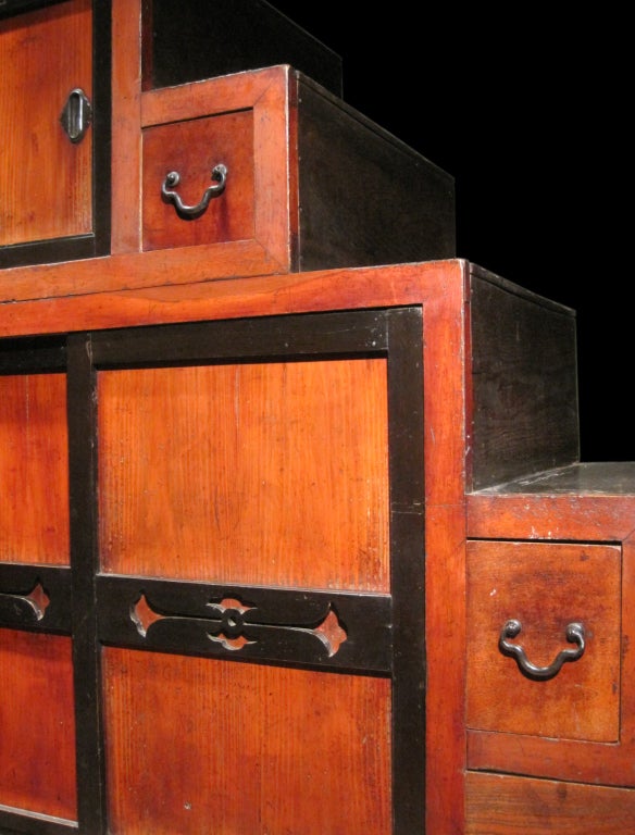 The kaidan dansu or step chest is one of the most distinctive tansu designs, being both cabinetry and architecture. This two-section example has keyaki or elm drawers and cypress framing with wiped lacquer. The sliding doors exhibit black lacquer