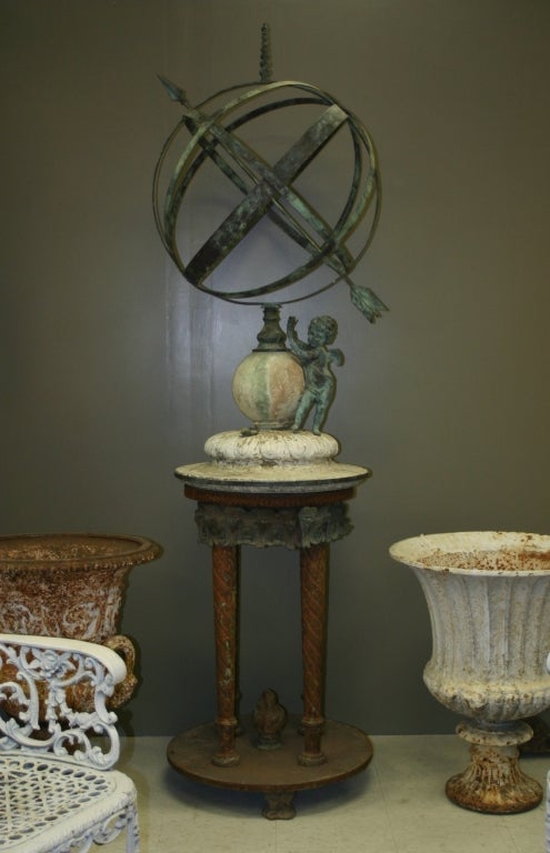 Monumental copper armillary mounted on a marble carved sphere and fluted base, which sits on an ornate cast iron stand.  Also mounted are a bronze snail and a very sweet cupid. One of our most ornamental sundials.