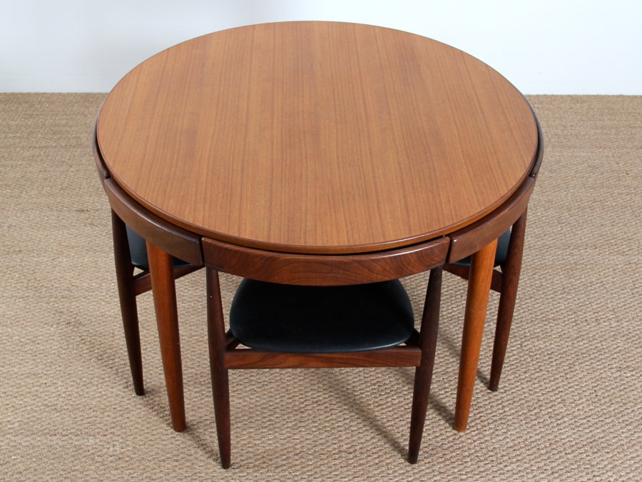 Danish teak dining set by Hans Olsen for Frem Rojle, 1952. Four pie-shaped three-legged chairs tuck perfectly underneath the table surface, creating a continuous skirt. Stackable chairs. 


Listed in the Furniture index of the Design Museum
