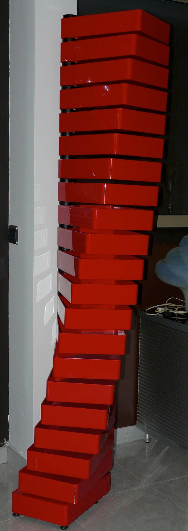 Chest of drawers with 20 drawers in red polish acrilyc material, revolving round a vertical metal support.
