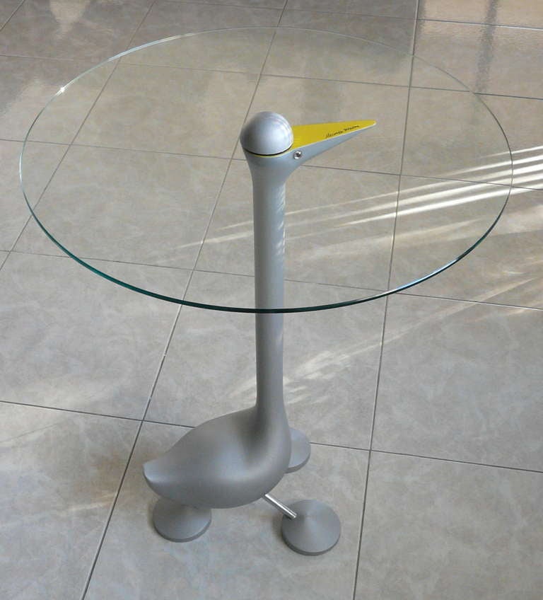Sirfo is Mendini's whimsical goose table. The piece is a signed original. With a frame in natural colour sandblasted cast aluminium, with yellow painted “beak”. The top is in tempered plate glass, thickness 6 mm.1986.