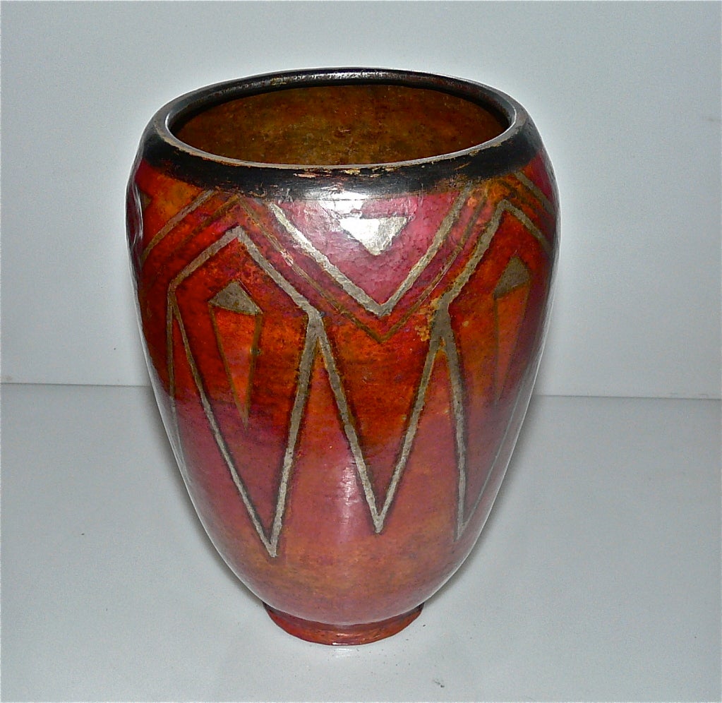 Large ovoid vase neck tightens in hammered copperware patina decorated with geometric silver on red background. Signed 