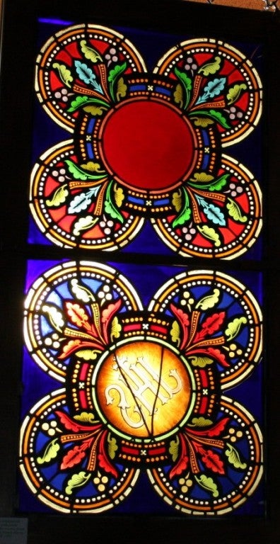 This is a finely made French Stained Glass Window from a church in France. There are two quatrefoil panels with floral vines and jewels set in a Gothic Tracery. One panel is marked with the lettersin Greek. 